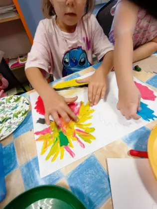 Dziewczynka rozciera plastelinę na przygotowanych wcześniej szablonach liści