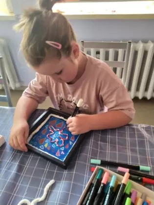 Dziewczynka maluje markerami obrazek.