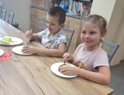 Chłopczyk i dziewczynka z połówek jabłek wykonują biedronki.