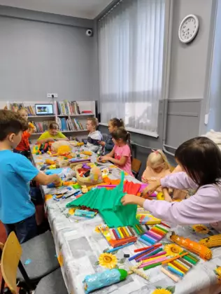 Dzieci przy stole wykonują kukurydziane ludziki.