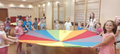 Dzieci trzymają w ręce rozciągnięta chustę animacyjną.