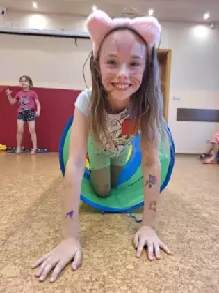 Dziewczynka na sali gimnastycznej przechodzi przez tunel.