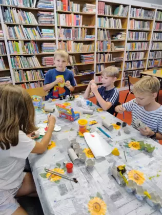 Dzieci malują farbami wytłaczanki z jajek i rolki papierowe.