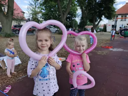 Dwie dziewczynki trzymają w rękach baloniki w kształcie serduszek.