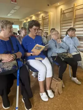 Uczestniczka spotkania czyta utwory Jana Kochanowskiego. W tle pozostali uczestnicy spotkania.