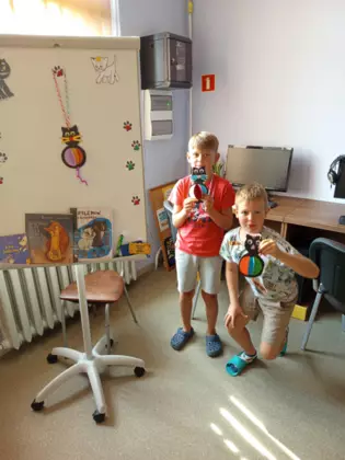 Uczestnicy zajęć trzymają gotowe koty-kukiełki.