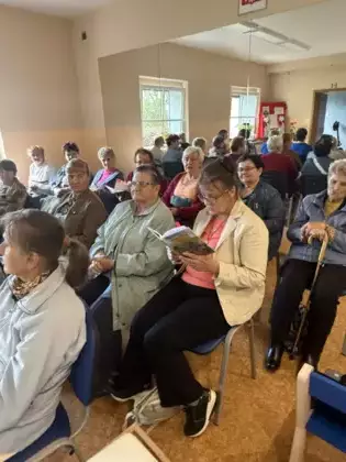 Uczestniczka spotkania czyta utwory Jana Kochanowskiego. W tle pozostali uczestnicy spotkania.