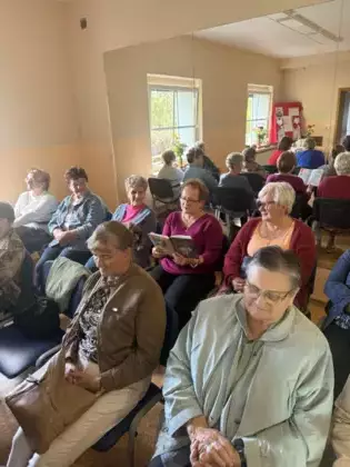 Uczestniczka spotkania czyta utwory Jana Kochanowskiego. W tle pozostali uczestnicy spotkania.