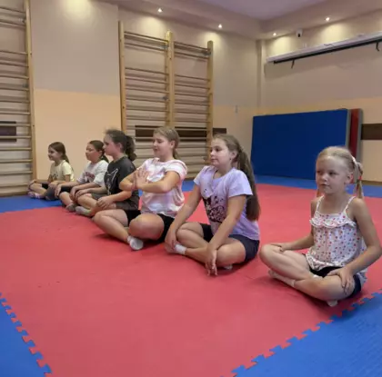 Dziewczynki wykonują gimnastykę na sali zabaw.