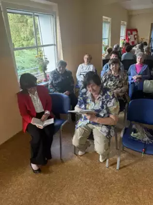 Uczestniczka spotkania czyta utwory Jana Kochanowskiego. W tle pozostali uczestnicy spotkania.