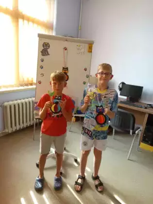 Uczestnicy zajęć trzymają gotowe koty-kukiełki.