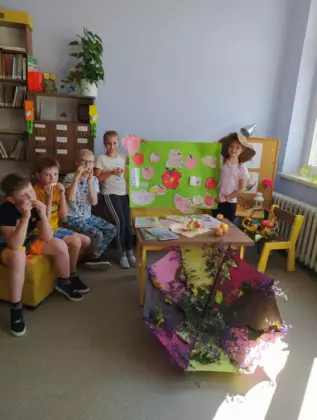 Dzieci słuchają czytanej książki w bibliotece.