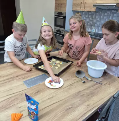 Dziewczyny pieką dla chłopców ciasteczka z kolorowymi drażetkami.