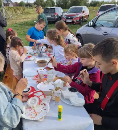 Dzieci siedzą przy stole i malują farbami figurki gipsowe.