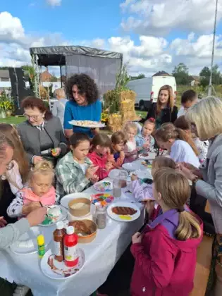 Pani wójt częstuje dzieci chlebem dożynkowym.