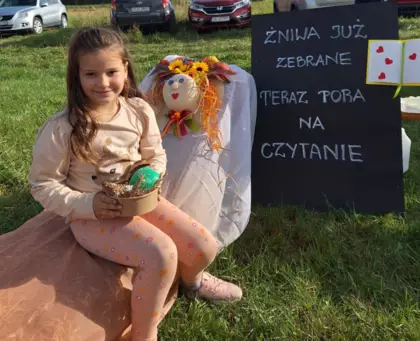 Dziewczynka trzyma w ręce koszyczek z gipsowymi figurkami pomalowanymi farbami.