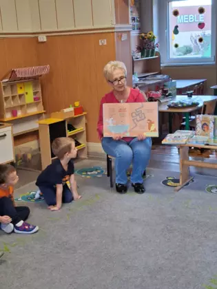 Dzieci słuchają bajki, którą czyta im Pani z biblioteki.