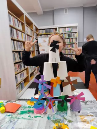 Dziewczynka pokazuje wiatraki zrobione z kubków papierowych.