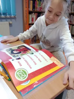 Uczestniczka zajęć czyta książeczkę pt. Listonosz Pat.