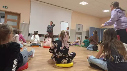 Dzieci siedzą na poduszkach i grają w kalambury.