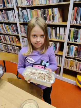 Dziewczynka w foremce ma przygotowane ciasto do upieczenia chleba.