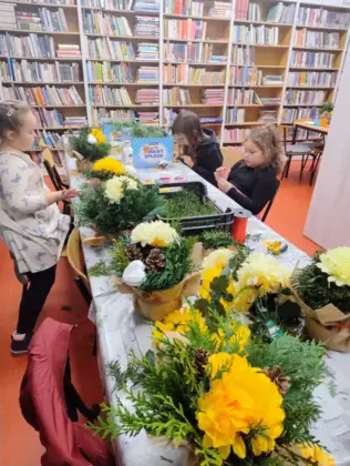 Dzieci z zielonych gałązek tworzą stroiki.