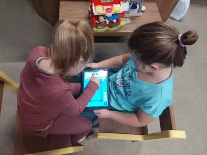 Dwie dziewczynki planują przejazd robota na tablecie.