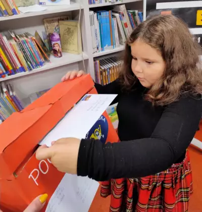 Dziewczynka wrzuca list do skrzynki.