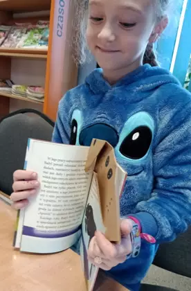 Dziewczynka pokazuje na kartkach książeczki jak używać swoich psich zakładek.