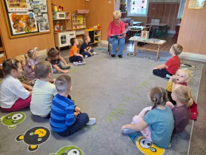 Dzieci słuchają bajki, którą czyta im Pani z biblioteki.