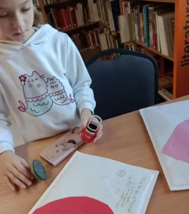 Dziewczynka adresuje kopertę.