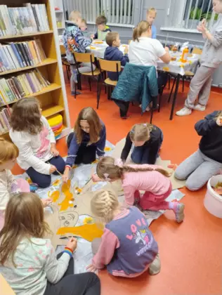 Dzieci kleją liśćmi Panią Jesień.