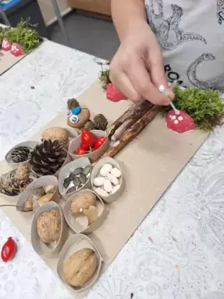 Chłopczyk maluje białą farbą kropki na muchomorze.