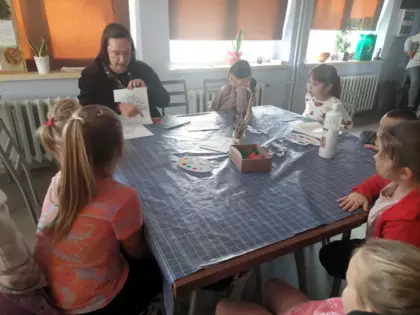 Pani z biblioteki tłumaczy dzieciom na czym polega praca plastyczna.