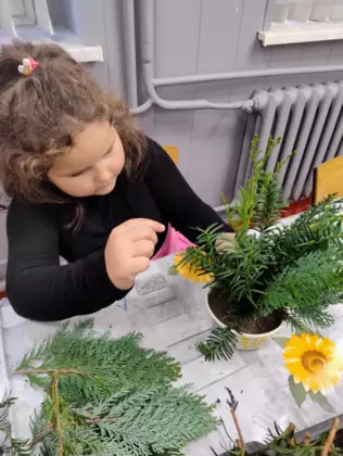 Dziewczynka wkłada gałązki do stroika.