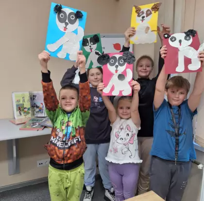 Dzieci pokazują swoje prace trzymając je wysoko do góry.