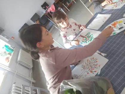 Dziewczynka w trakcie robienia  jesiennego drzewka.