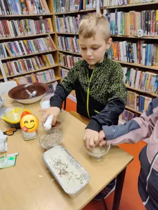 Dzieci sypią ciasto na chleb ziarenkami.