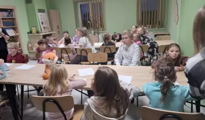 Dzieci siedzą przy stoliku rozwiązując zagadki logiczne.