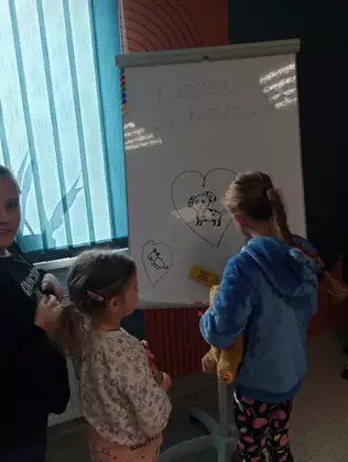 Dzieci na tablicy rysują psy.