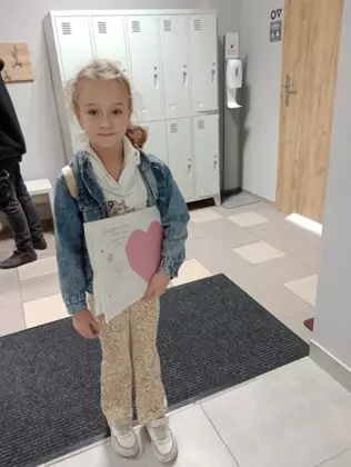 Dziewczynka trzyma w rękach listy, które napisała w trakcie zajęć.