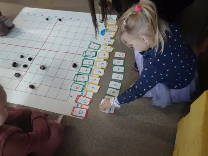 Dziewczynka koduje trasę na macie dla robota Genibota, tak aby dotarł on kasztana.