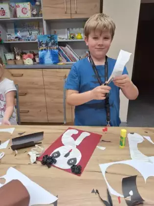 Chłopczyk wycina z gazety pieska.