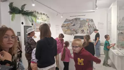 Dzieci w muzeum szukają dinozaurów.