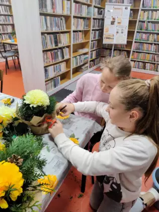 Dzieci z zielonych gałązek tworzą stroiki.