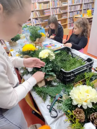 Dzieci z zielonych gałązek tworzą stroiki.