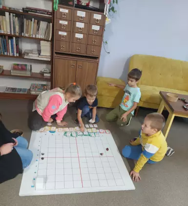 Dziewczynka i trzech chłopców kodują trasę dla robota.
