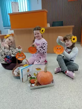 Trzy dziewczynki prezentują wykonane przez siebie dynie.