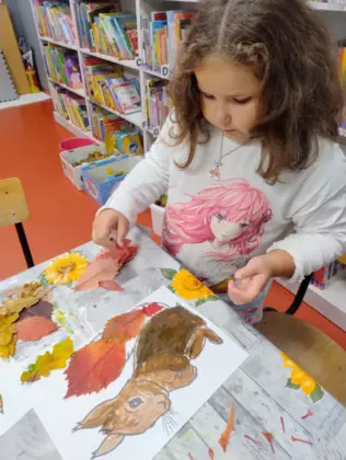 Dziewczynka okleja ogon wiewiórki liśćmi.