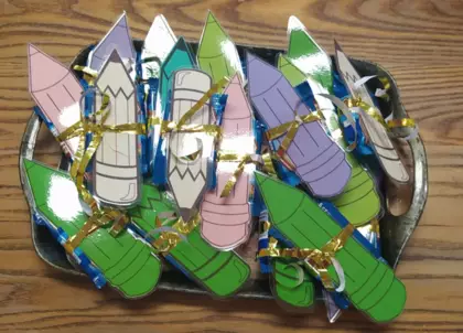 Upominki dla przedszkolaków, zakładka w kształcie ołówka oraz batonik.